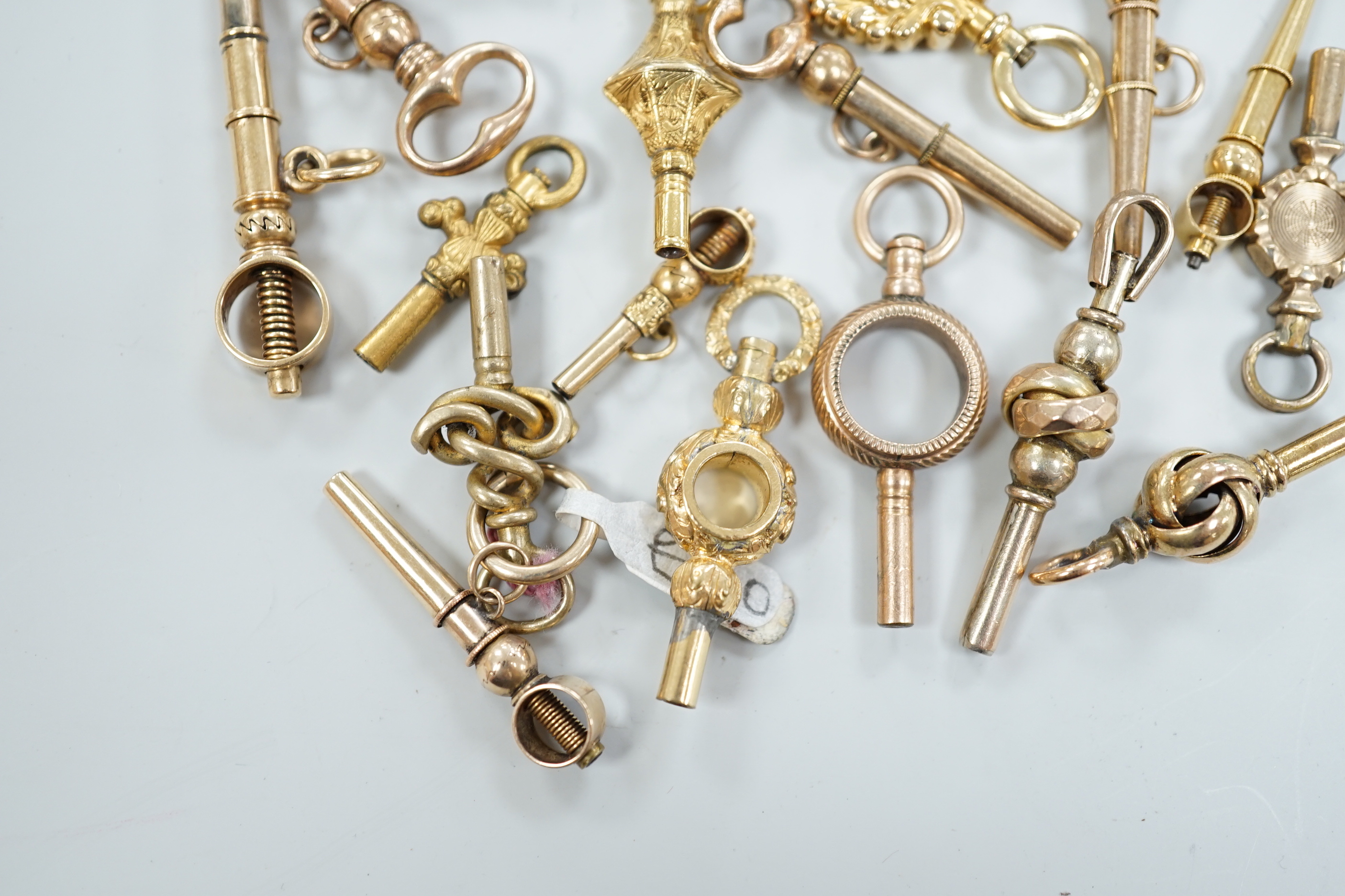 Twenty assorted mainly 19th century yellow metal small watch keys, including trade insignia, bloodstone set and keys to be turned in one direction, largest 37mm, together with a 19th century yellow metal overlaid and aga
